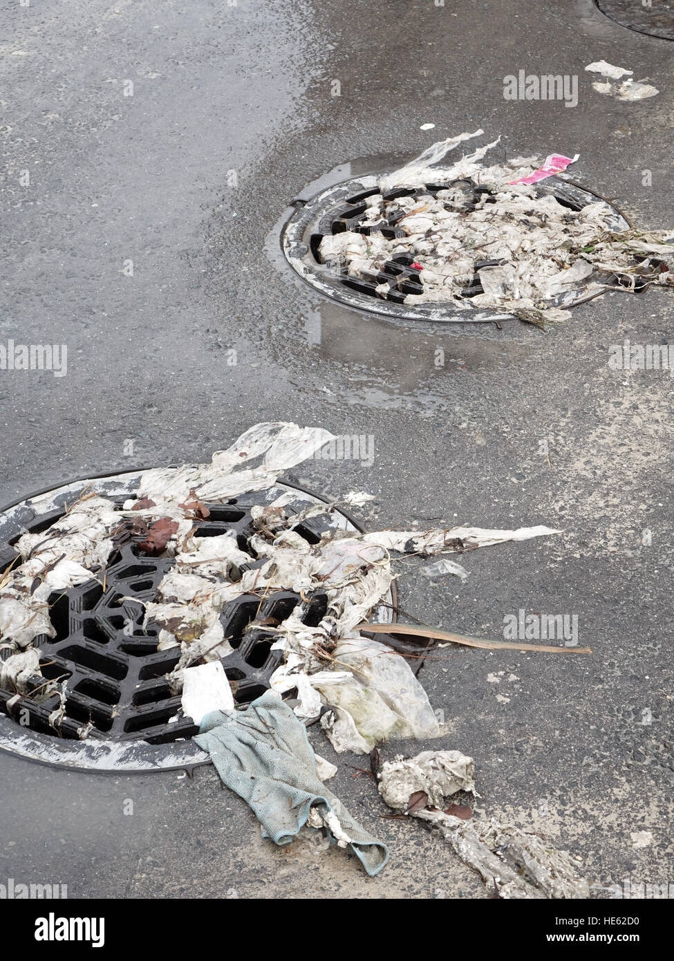Clogged drain cover or grate. Sewage and litter cover the road