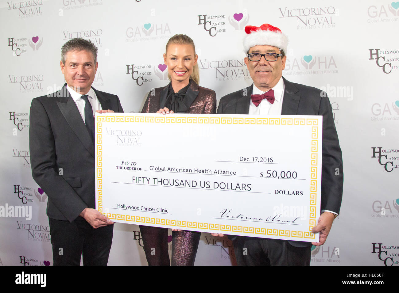 Beverly Hills, California, USA. 17th December, 2016. Dr. Alexander Gershman, Hannah Noval, and Victorino Noval hold a check representing the $50,000 donation check from Victorino Noval at the Victorino Noval Foundation Christmas Party Benefiting the Global American Health Alliance at the Noval Estate in Beverly Hills, California, USA. The Global American Health Alliance is a non-profit organization that was created to provide healthcare access to individual diagnosed and living with cancer. © Sheri Determan/Alamy Live News Stock Photo