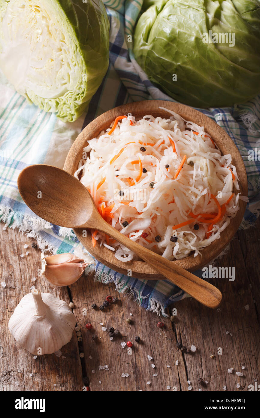 sauerkraut and carrots in a wooden plate vertical view from above, rustic style Stock Photo