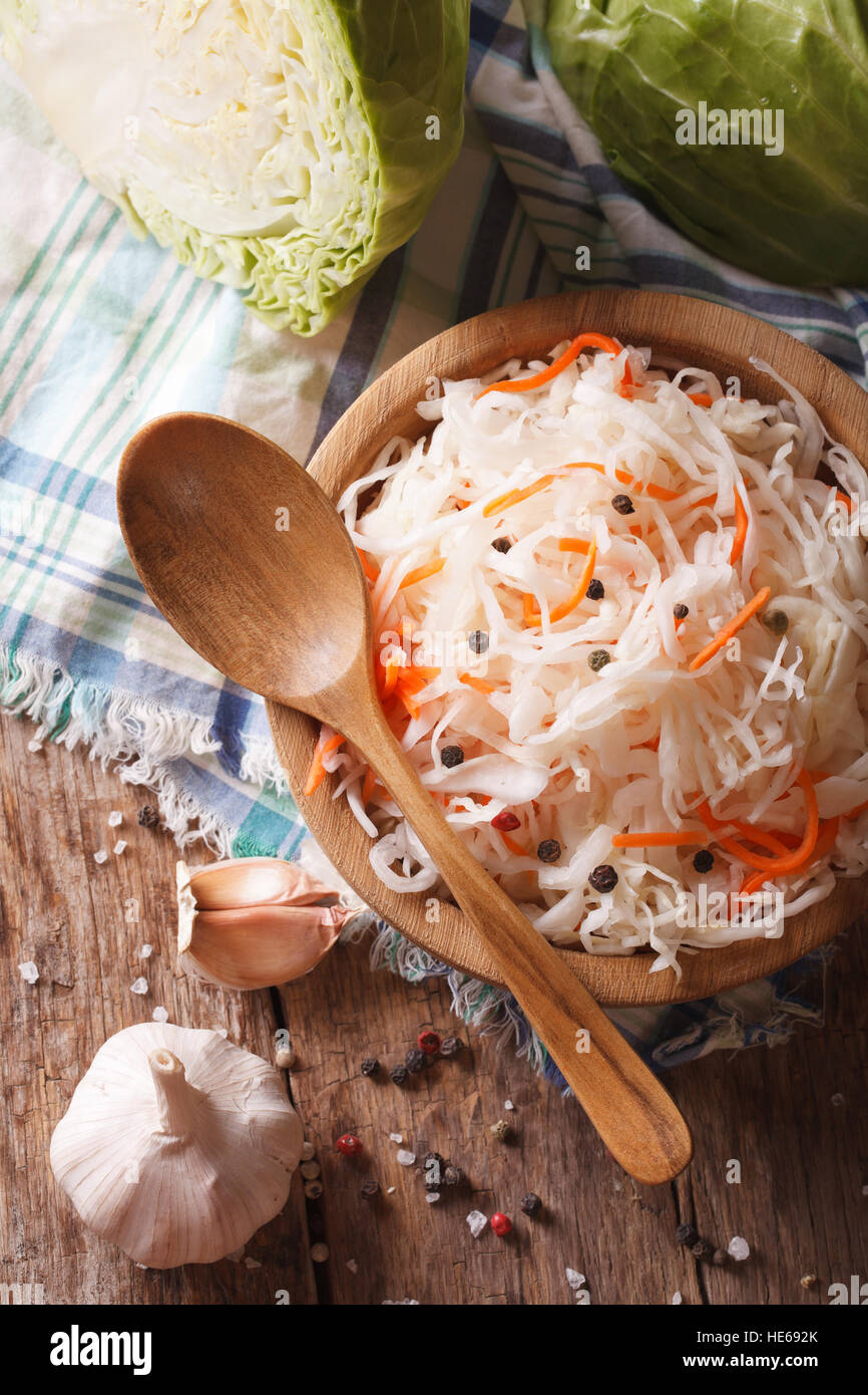 sauerkraut and carrots in a wooden plate close up vertical view from above, rustic style Stock Photo
