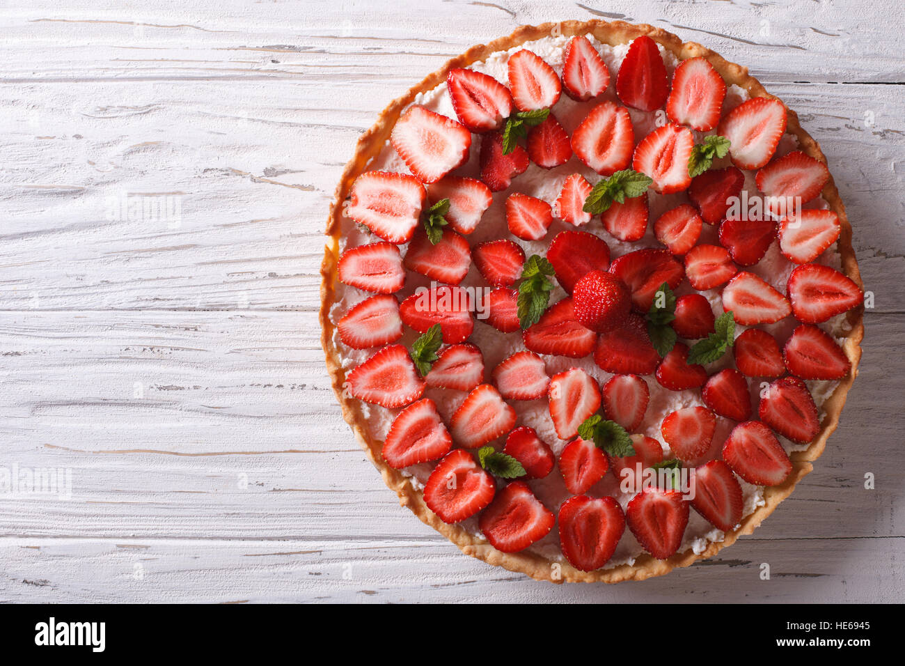 Delicious tart with fresh strawberries and soft cheese on the table. horizontal view from above Stock Photo