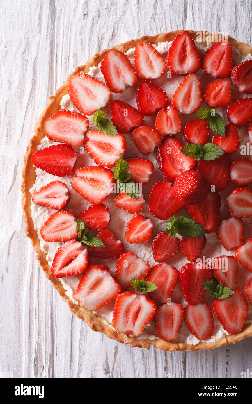 Delicious tart with fresh strawberries and soft cheese on the table. Vertical view from above Stock Photo