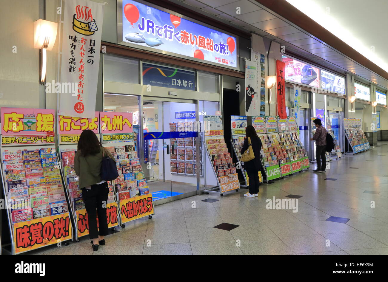 People read holiday brochures at Japan Travel travel agency at Osaka railway station in Osaka Japan. Stock Photo
