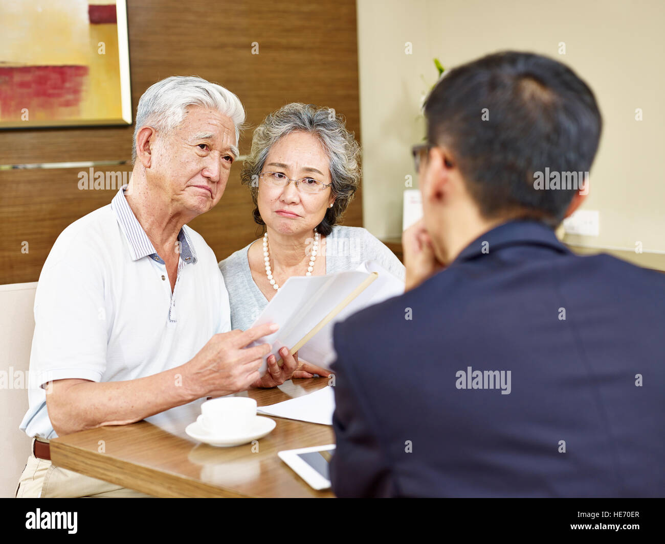 senior asian couple looking skeptical during meeting with insurance agent Stock Photo