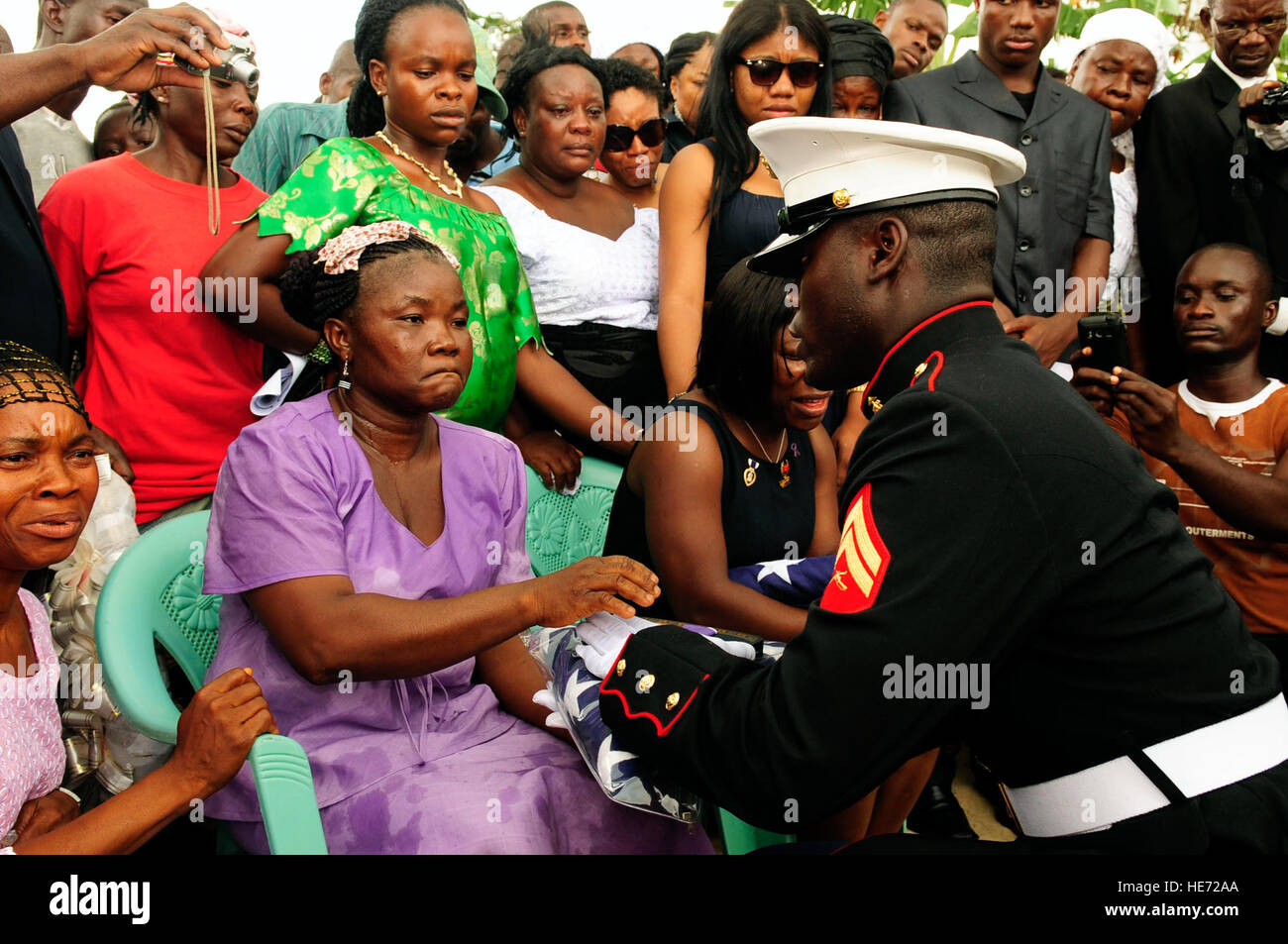 U.S. Marine Corps Cpl. Michael Wiles, right, presents a U.S. flag to Famata Kar, the mother of Lance Cpl. Abraham Tarwoe, at a memorial service in Flehla, Liberia, May 17, 2012. Tarwoe, who was born in Liberia but immigrated to the United States before joining the Marine Corps, died from wounds suffered in combat in Helmand province, Afghanistan, April 12, 2012. Wiles escorted Tarwoe’s body back to Liberia. Tarwoe was with the 2nd Battalion, 9th Marine Regiment and Wiles was with the 2nd Marine Special Operations Battalion.  1st Lt. Mark Lazane, U.S. Air Force Stock Photo