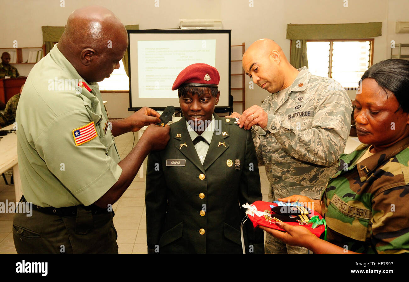 MONROVIA, Liberia-Armed Forces of Liberia Maj. Geraldine George, center, AFL senior legal officer, is presented her new rank by Maj. Gen. Suraj Alao Abdurrahman, Armed Forces of Liberia command officer in charge, left and U.S. Air Force Maj. Kevin Ingram, a native of Lifle, Ill., legal adviser to the AFL, during a promotion ceremony at Barclay Training Center in Monrovia, Liberia Feb. 20. George was one of 565 AFL personnel to be promoted during the most recent promotion cycle. She represents the growing opportunities for women in the AFL and currently is the highest ranking female serving in  Stock Photo