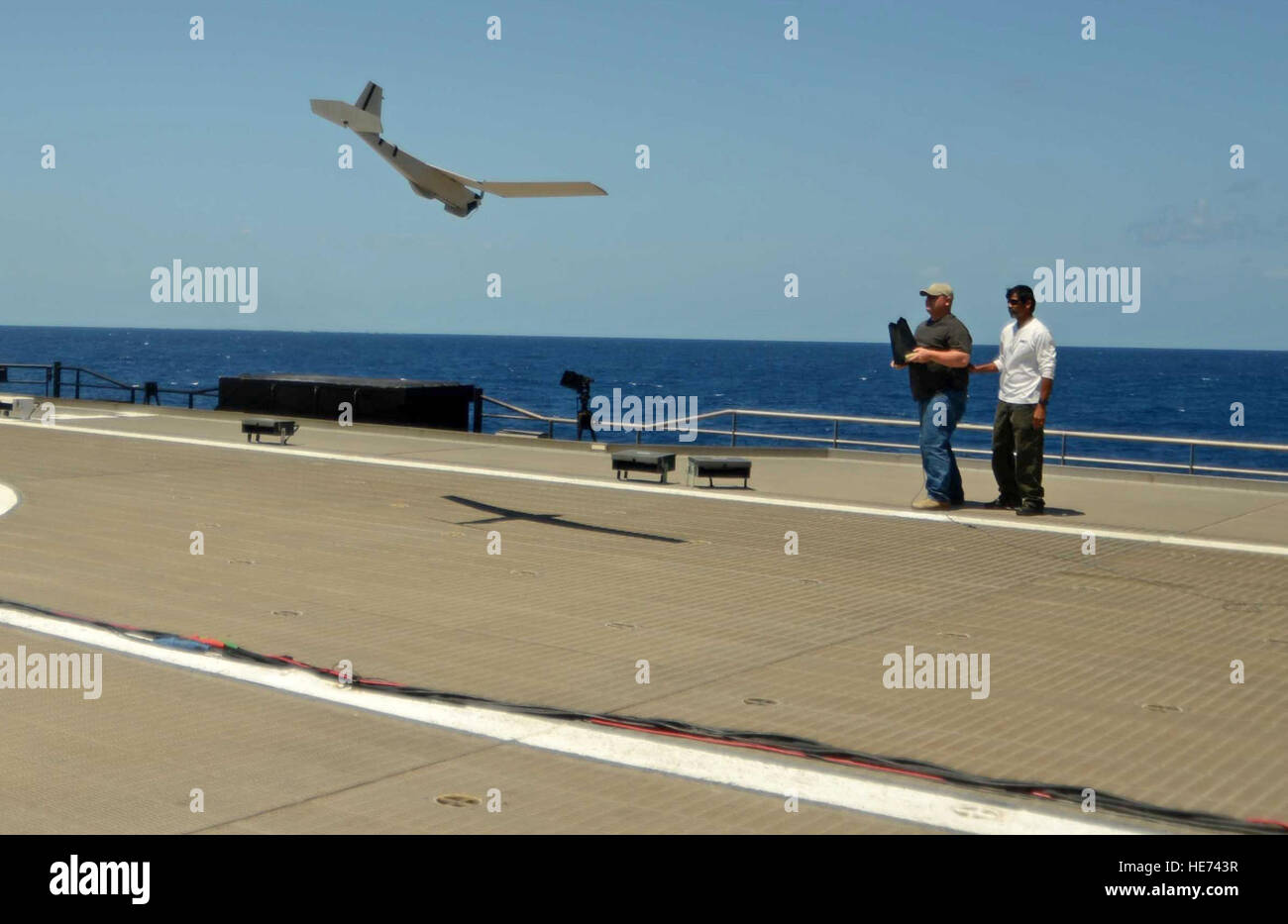Justin Sellers, left, an unmanned air systems flight operator, lands a Puma unmanned aircraft system as fellow operator Stu Orozco looks on aboard high speed vessel Swift (HSV-2) April 25, 2013, in the Caribbean Sea near Key West, Fla. The Puma?s flight was part of an at-sea demonstration of future counter-transnational organized crime operations as part of Operation Martillo. Martillo is a joint, interagency and multinational collaborative effort to deny transnational criminal organizations air and maritime access to the littoral regions of the Central American isthmus.  Master-at-Arms Seaman Stock Photo