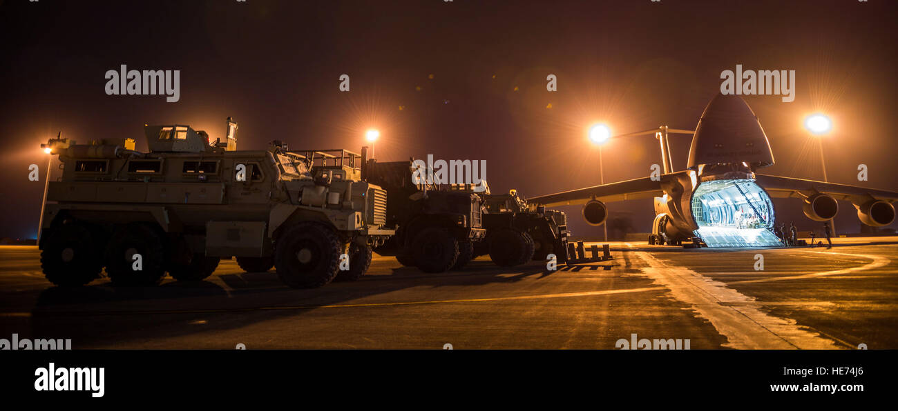 Airmen from the 9th Airlift Squadron and 455th Expeditionary Aerial Port Squadron with Marines from the Marine Expeditionary Brigade prepare to load vehicles into a C-5M Super Galaxy Oct. 6, 2014, at Camp Bastion, Afghanistan. Airmen and Marines loaded more than 266,000 pounds of cargo onto the C-5M as part of retrograde operations in Afghanistan. Aircrews for the retrograde operations, managed by the 385th Air Expeditionary Group Detachment 1, surpassed 11 million pounds of cargo transported in a 50-day period. During this time frame, crews under the 385th AEG broke Air Mobility Command’s ope Stock Photo
