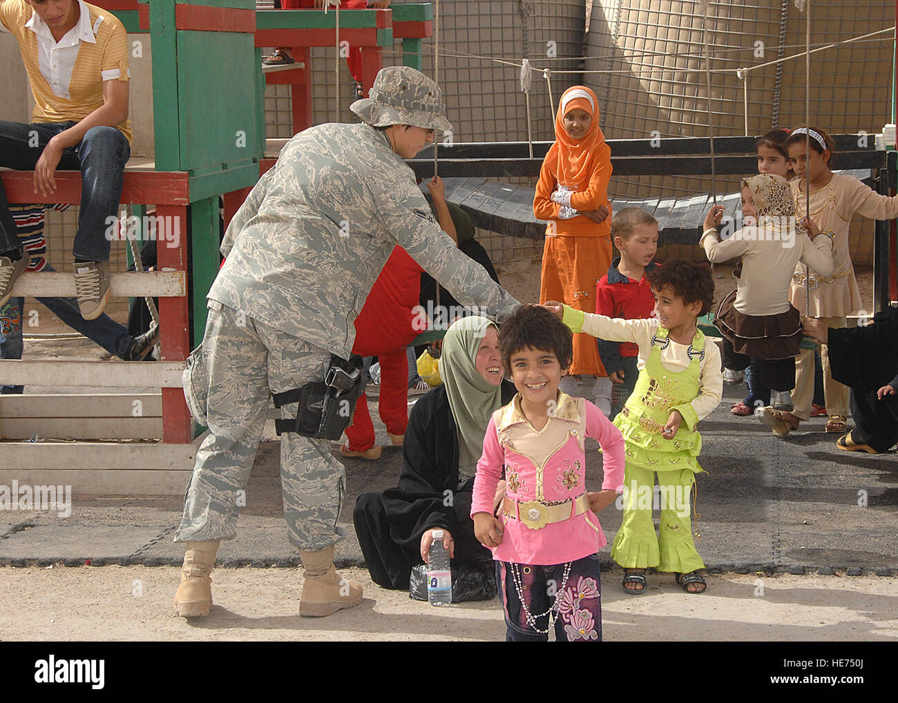 A U.S. Air Force security forces member from the 586th Air Expeditionary Group plays with Iraqi children on Sept. 29, 2008, at Camp Bucca, Iraq, while they wait for transport to the detainee visitation center. The 586th AEG provides security and transport to the center for nearly 400 visitors who are allowed to visit daily with detainees being held at the Theater Internment Facility. Stock Photo
