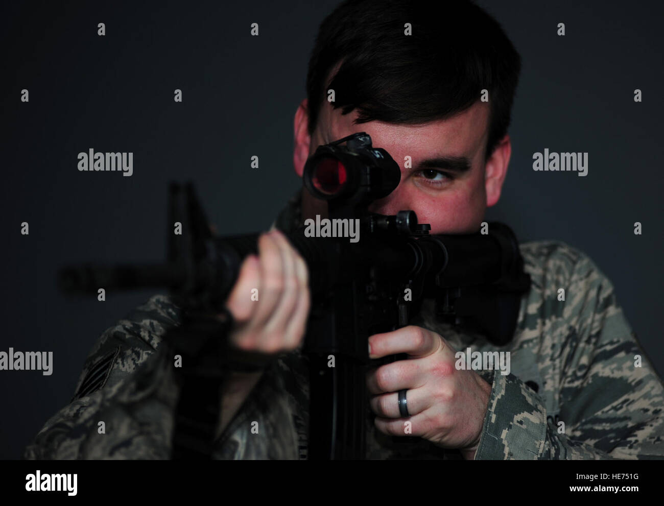 U.S. Air Force Staff Sgt. Ryan Gulley, 633rd Security Forces Squadron training instructor, fires at a simulated target at Langley Air Force Base, Va., Jan. 26, 2015. The new firearms simulator allows Airmen to gain real-world knowledge and experience through projections of real-life scenarios.  Airman 1st Class Areca T. Wilson Stock Photo