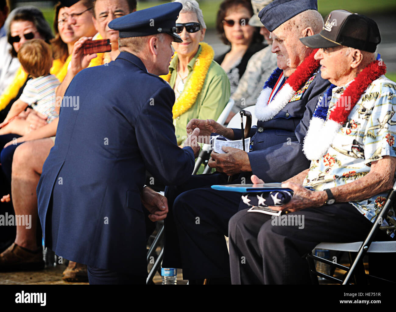 Col. Johnny Roscoe, 15th Wing commander, shakes the hand of Kenneth Ford, a Hickam Field survivor, during a remembrance ceremony, Dec. 7, at Joint Base Pearl Harbor-Hickam, Hawaii. Ford enlisted in the Army Air Corps at the age of 15, after lying about his age. On Dec 6, he had a layover at Hickam Field en route to Dutch Harbor, Alaska. Early Sunday morning while he was taking a shower, the first bombs dropped on Hickam Field. Ford defended Hickam field on the shores of Fort Kamehameha Beach. Ford later went on to fight in the European theater, where he became a German prisoner of war. After h Stock Photo