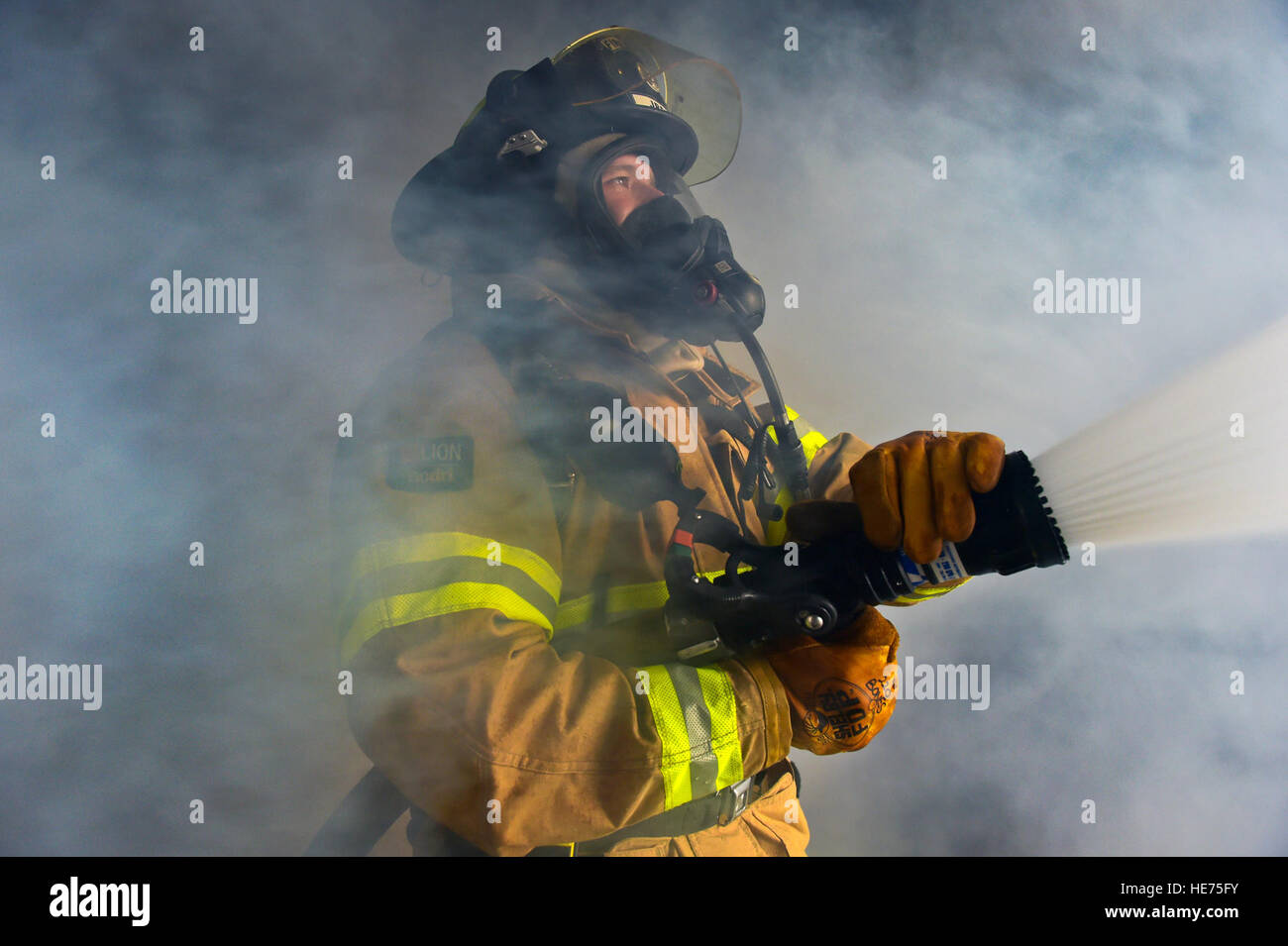 Adam Bowens, a firefighter assigned to the 673rd Civil Engineer Squadron, demonstrates to visiting U.S. Air Force Academy cadets how to evacuate smoke from a building utilizing a water hose while conducting live-fire training on Joint Base Elmendorf-Richardson, Alaska, May 20, 2015. The training provided the cadets, studying civil engineering, the opportunity to work with Airmen and noncommissioned officers in their field of choice. Justin Connaher) Stock Photo