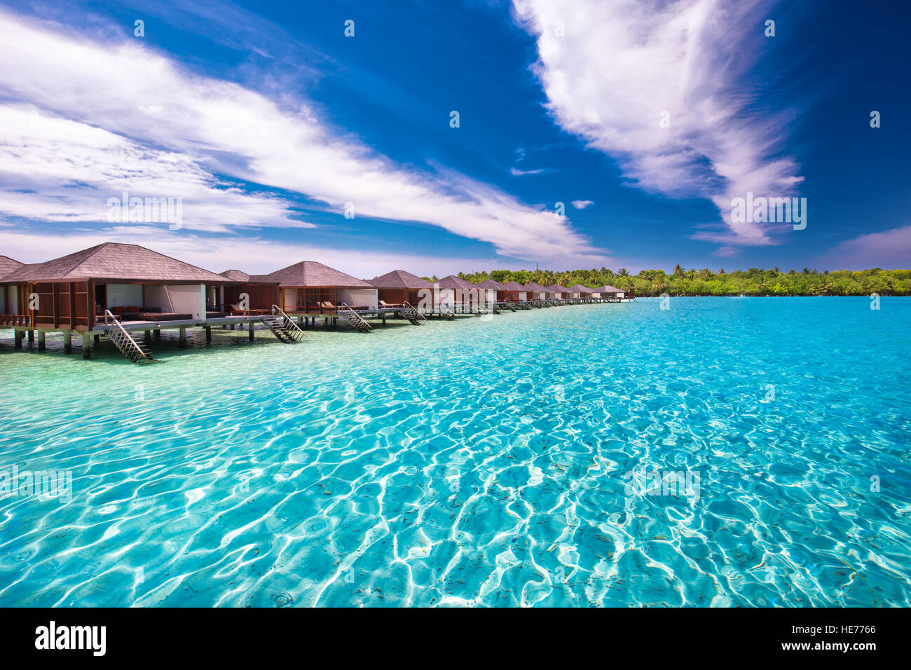 Luxurious water bungalows on tropical island with tourquise clear water. Stock Photo