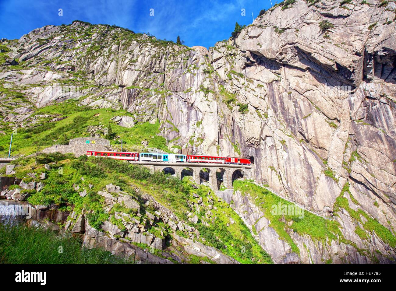 Train on Teufelsbruecke - Devil's bridge on Gotthard mountain pass near Andermatt in Swiss Alps Stock Photo