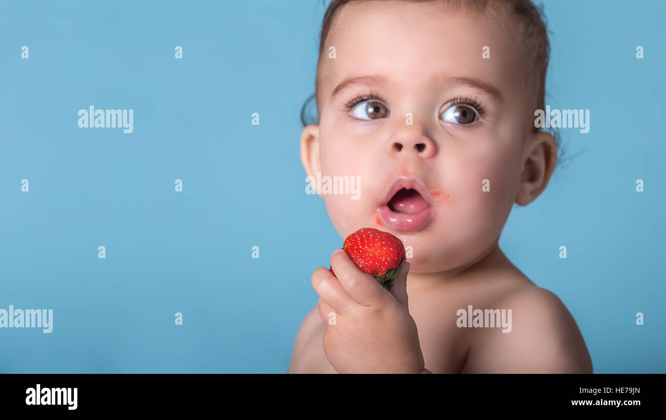 Pretty Toddler Girl Holding Ripe Red Strawberry, Focus on Fruit with Blurry Face and Background Stock Photo