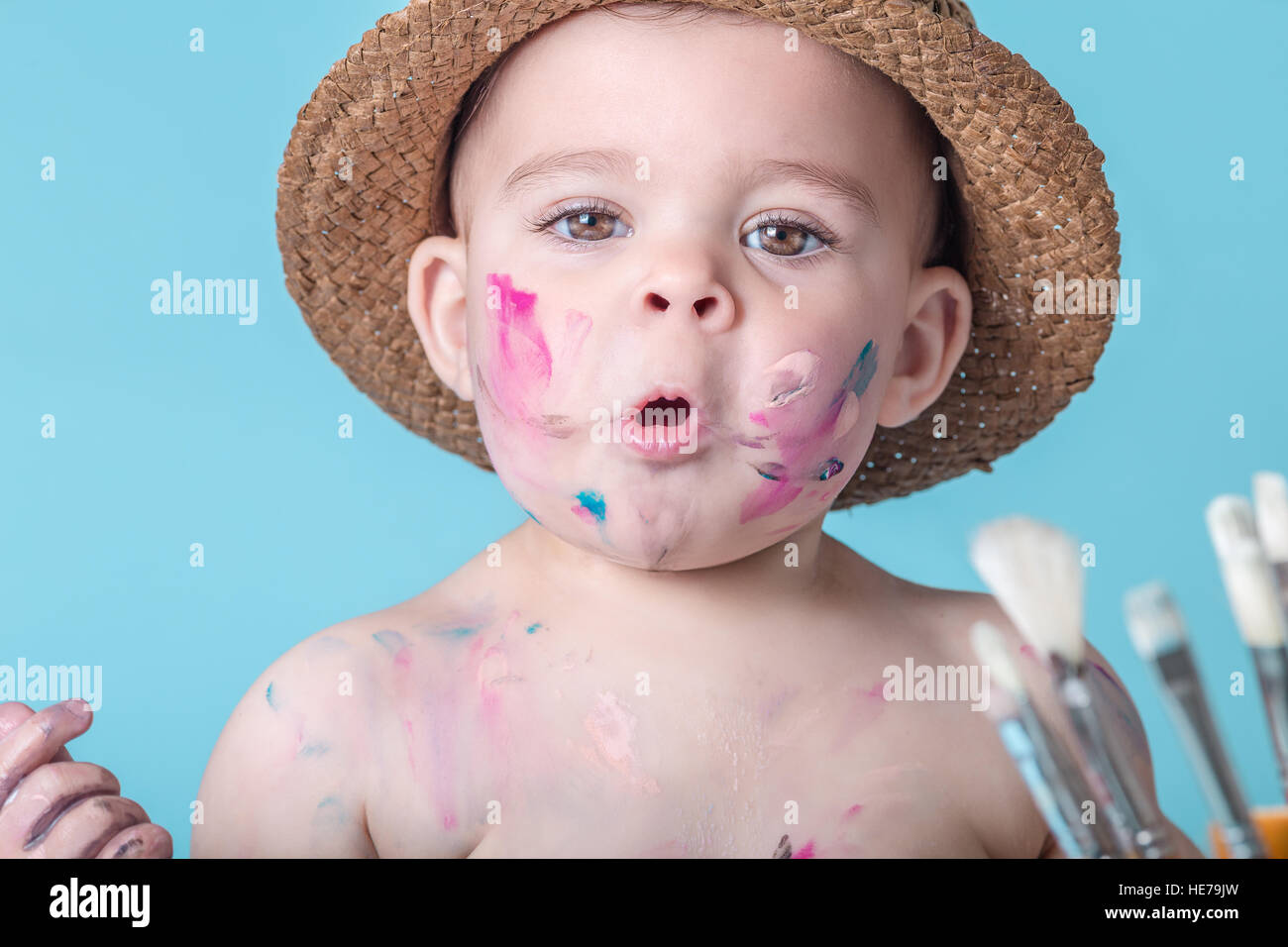 Adorable Toddler Girl Covered in Paint on Plain Blue Background Stock Photo