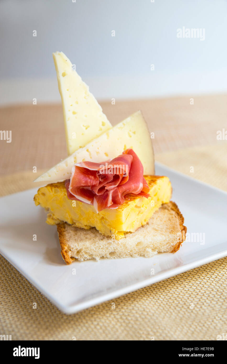 Spanish tapa made of Manchego cheese, Iberian ham and Spanish omelet on