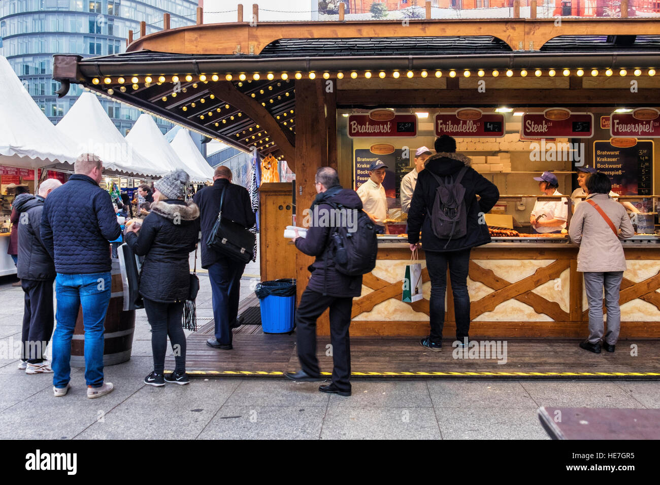 Berlin, Mitte, Potsdamerplatz. People buying hotdogs, bratwurst, frikadelle at German Christmas market stall Stock Photo