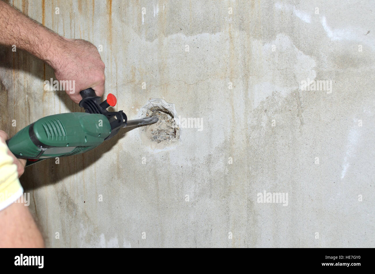 Electric chiseling machine making hole in a concrete wall Stock Photo