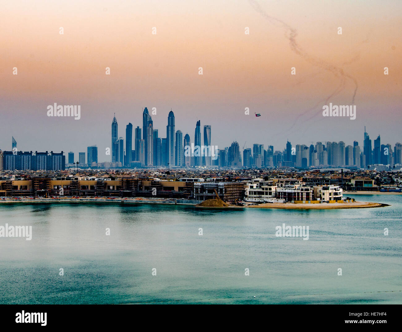 Sunset over Dubai on UAE flag day with a biplane flying the UAE flag in the sky Stock Photo