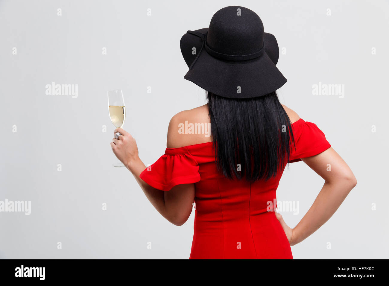 Photo of woman in black hat and red dress standing back in studio Stock ...