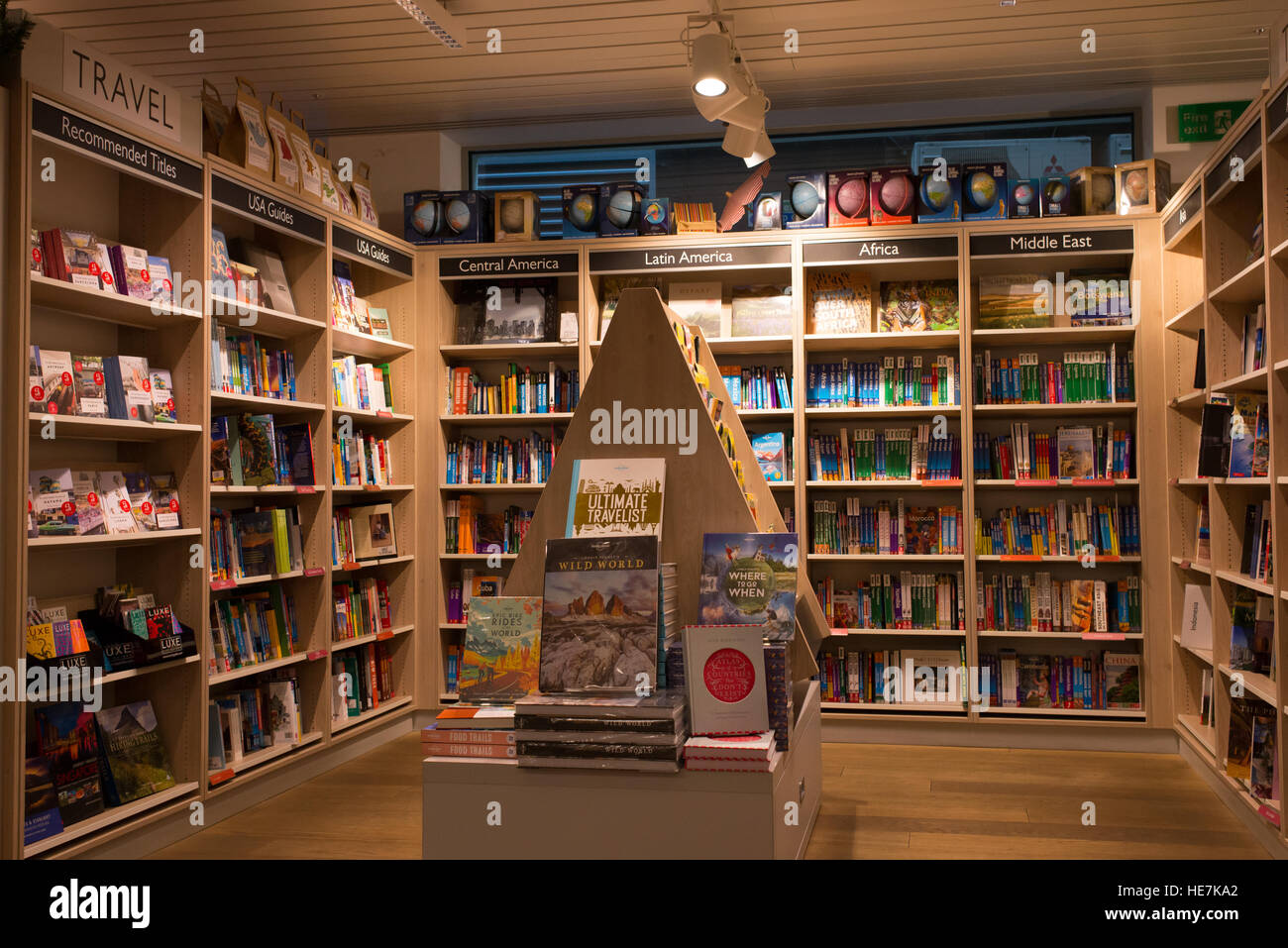 Interior of a modern bookshop with wooden shelves full of books. Section of travel books and guides. Stock Photo