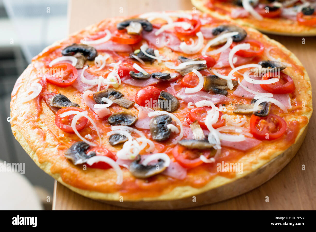 Homemade pizza with ham, mushrooms, tomatoes and onion before oven. Selective focus, close up shot Stock Photo