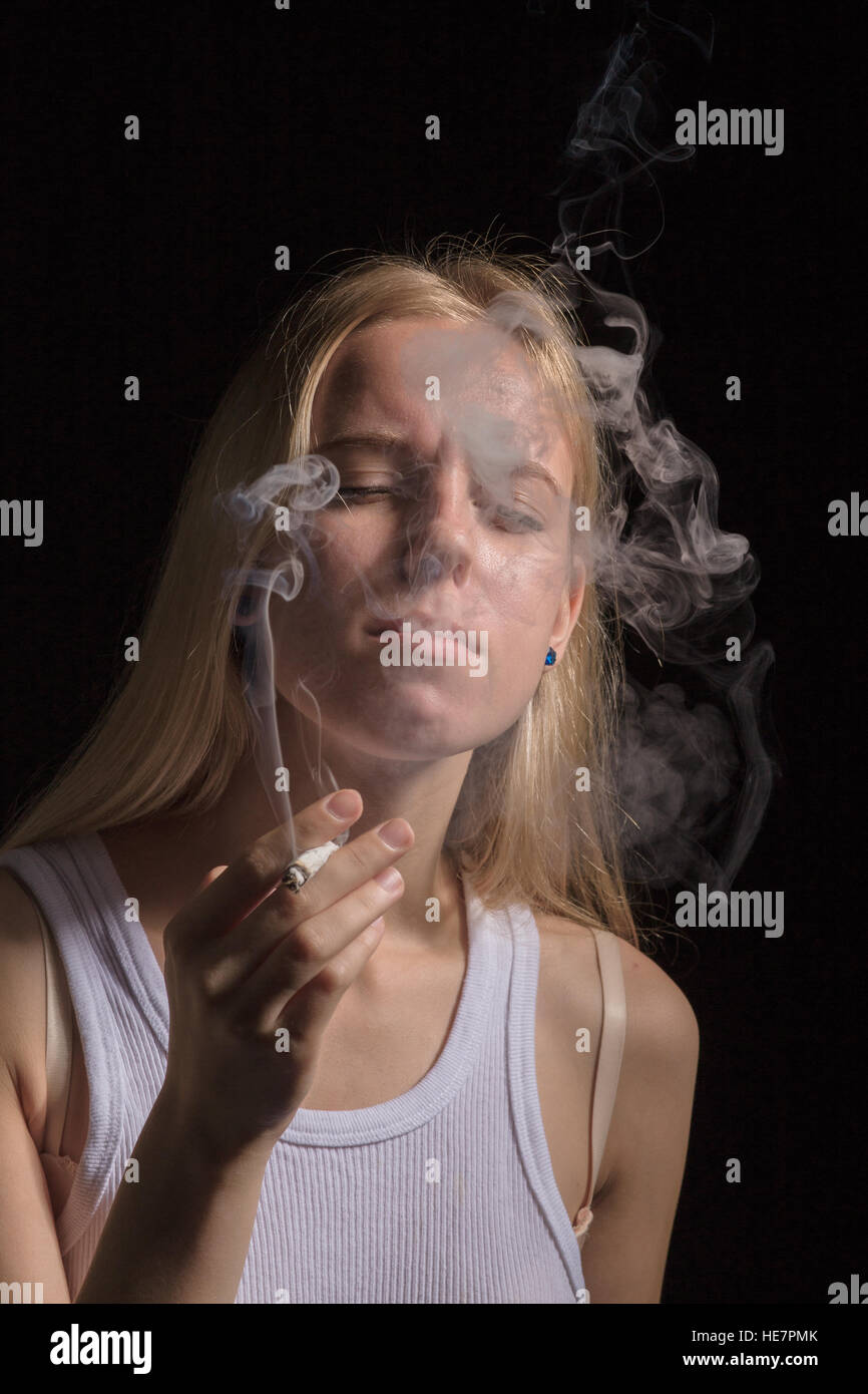 blond young woman smoking on black background Stock Photo - Alamy