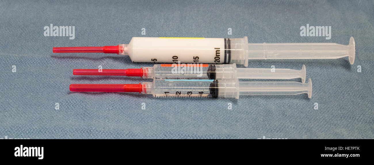 Three syringes with red capped needles containing labeled generic