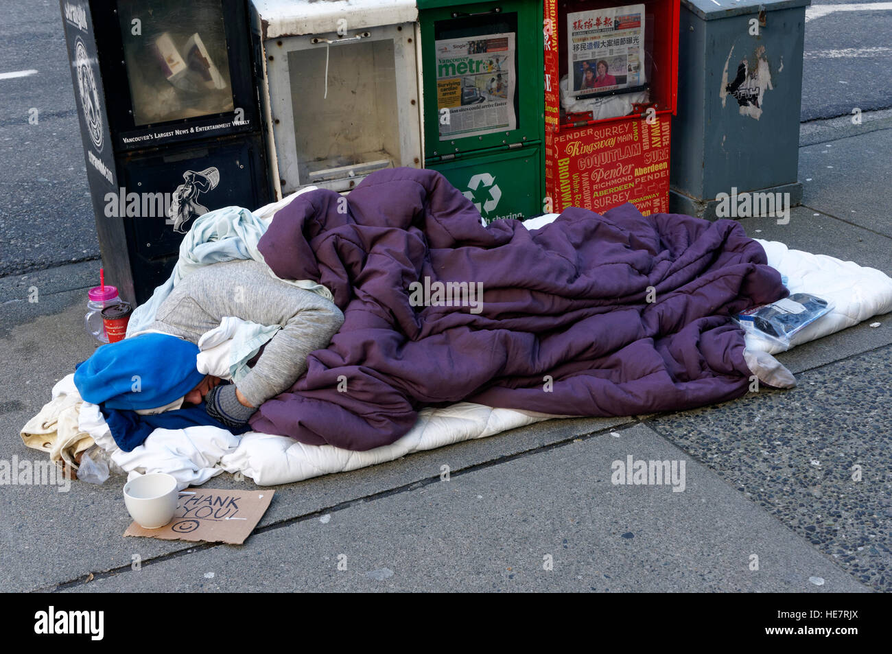 A homeless man sleeping on the sidewalk in cold weather, Vancouver, British Columbia, Canada Stock Photo