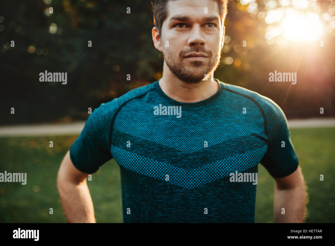 Close up portrait of fit young man in sportswear standing outdoors. Confident fitness male model in park. Stock Photo