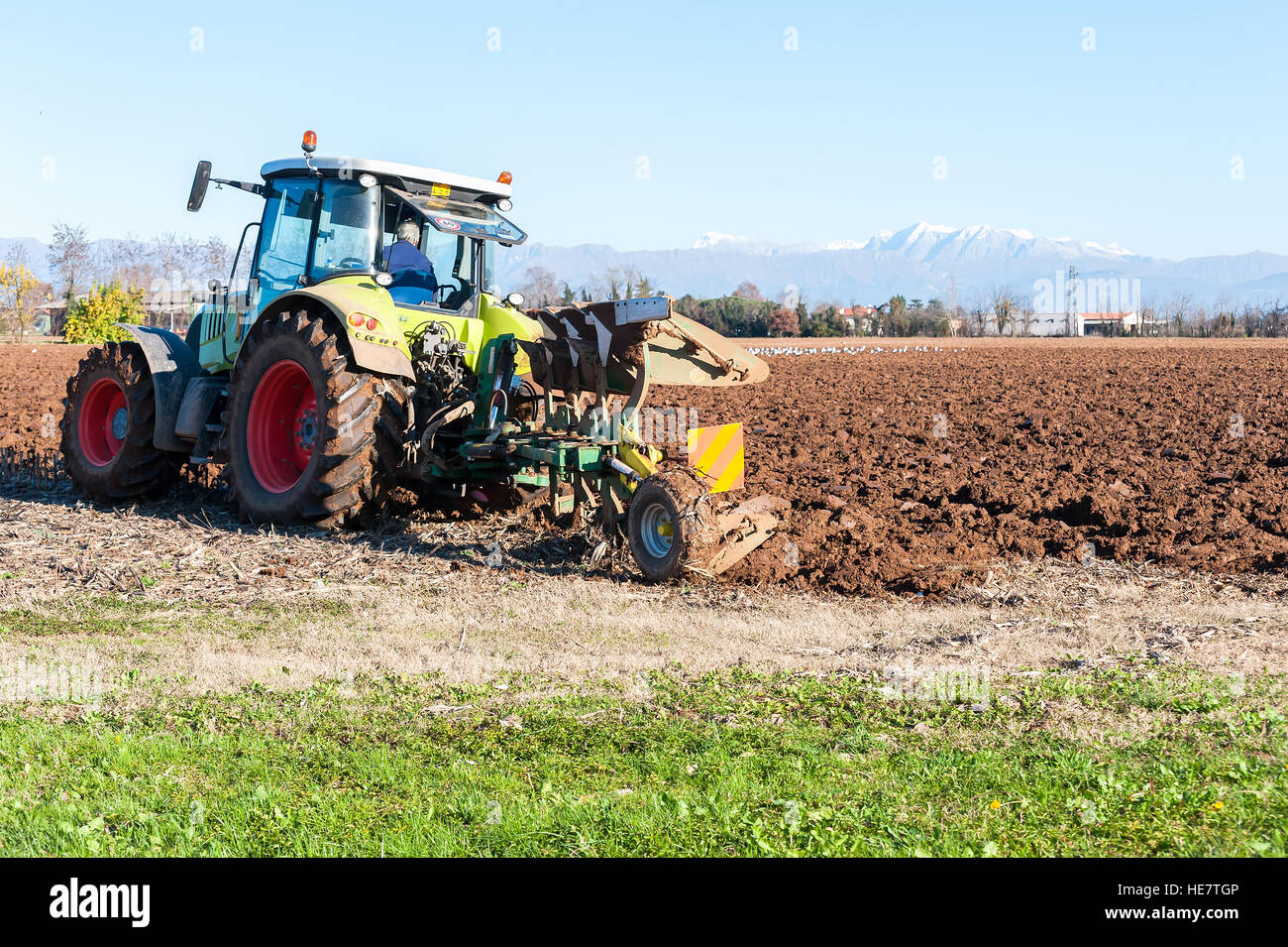 Tractor with plow. Plowing field in sunny day Stock Photo - Alamy