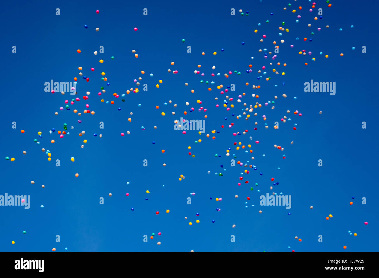 Hundreds of colorful balloons are flying through the blue cloudless sky Stock Photo