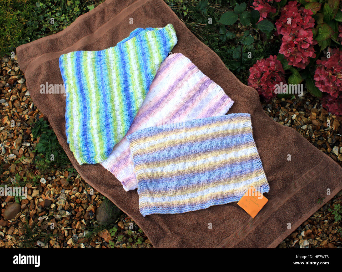 Three blankets for babies have been hand knitted and are displayed in a
