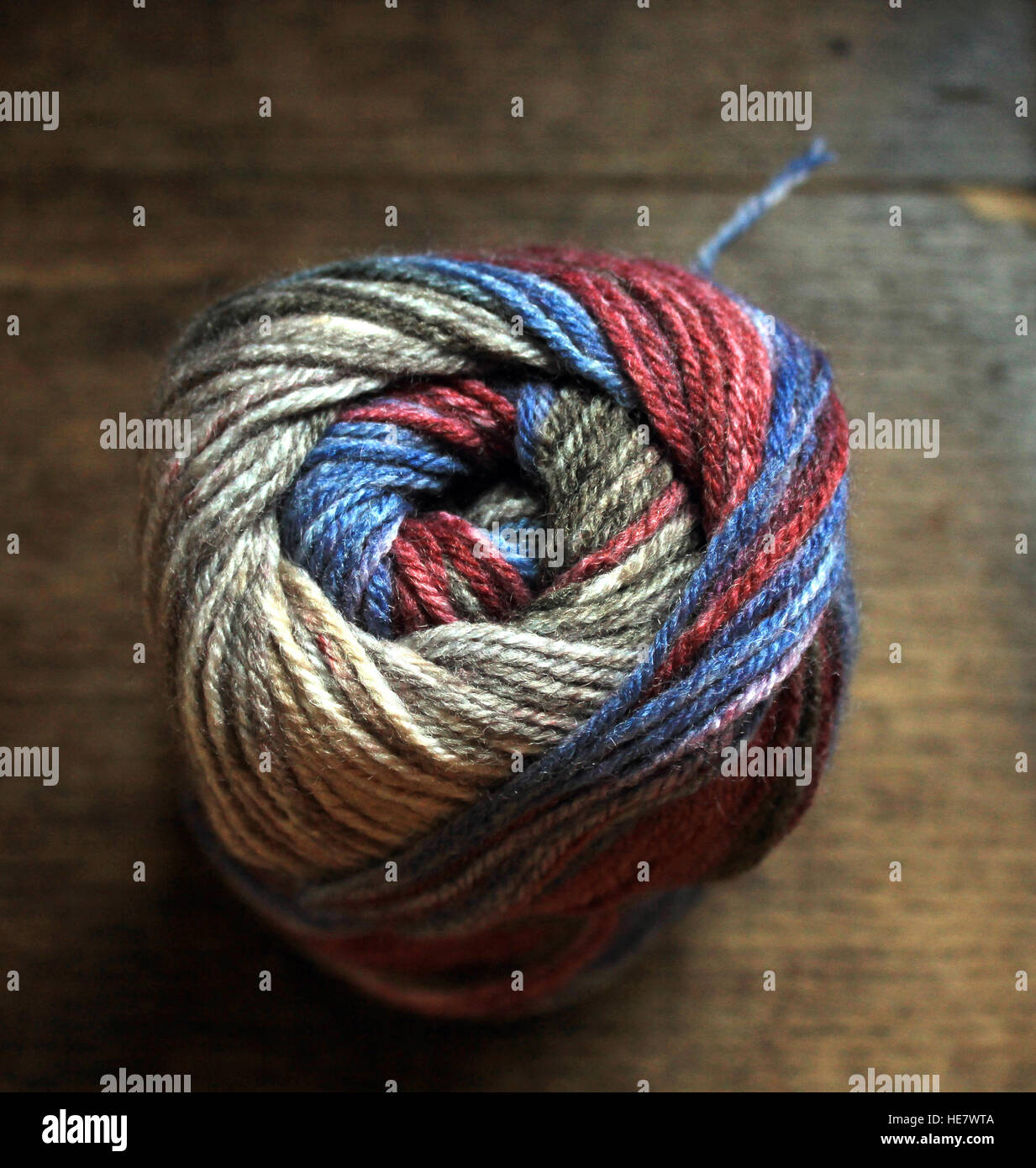A ball of hand knitting yarn in shades of grey, blue and maroon