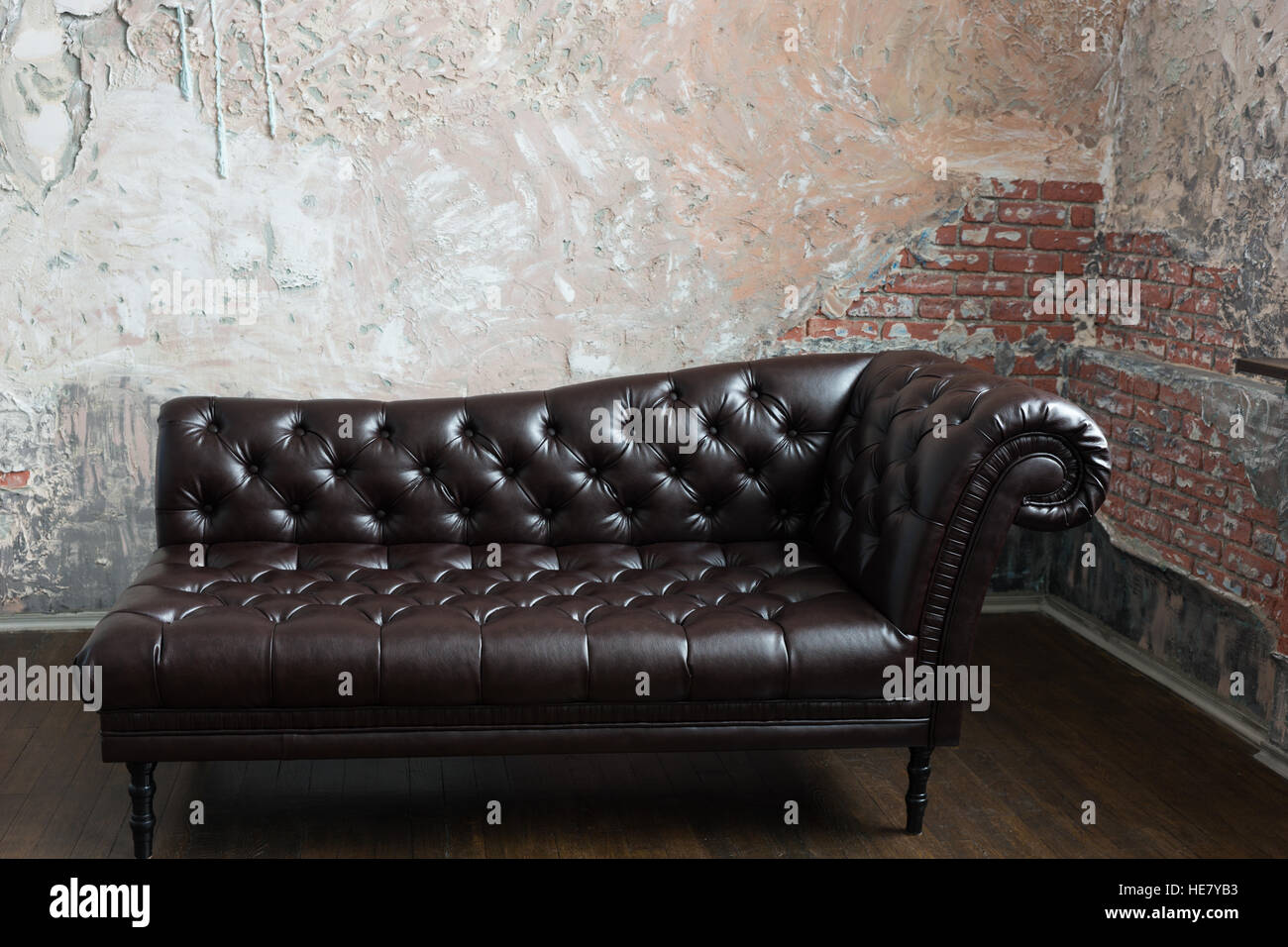 Leather sofa in the English style in the room with old red brick walls