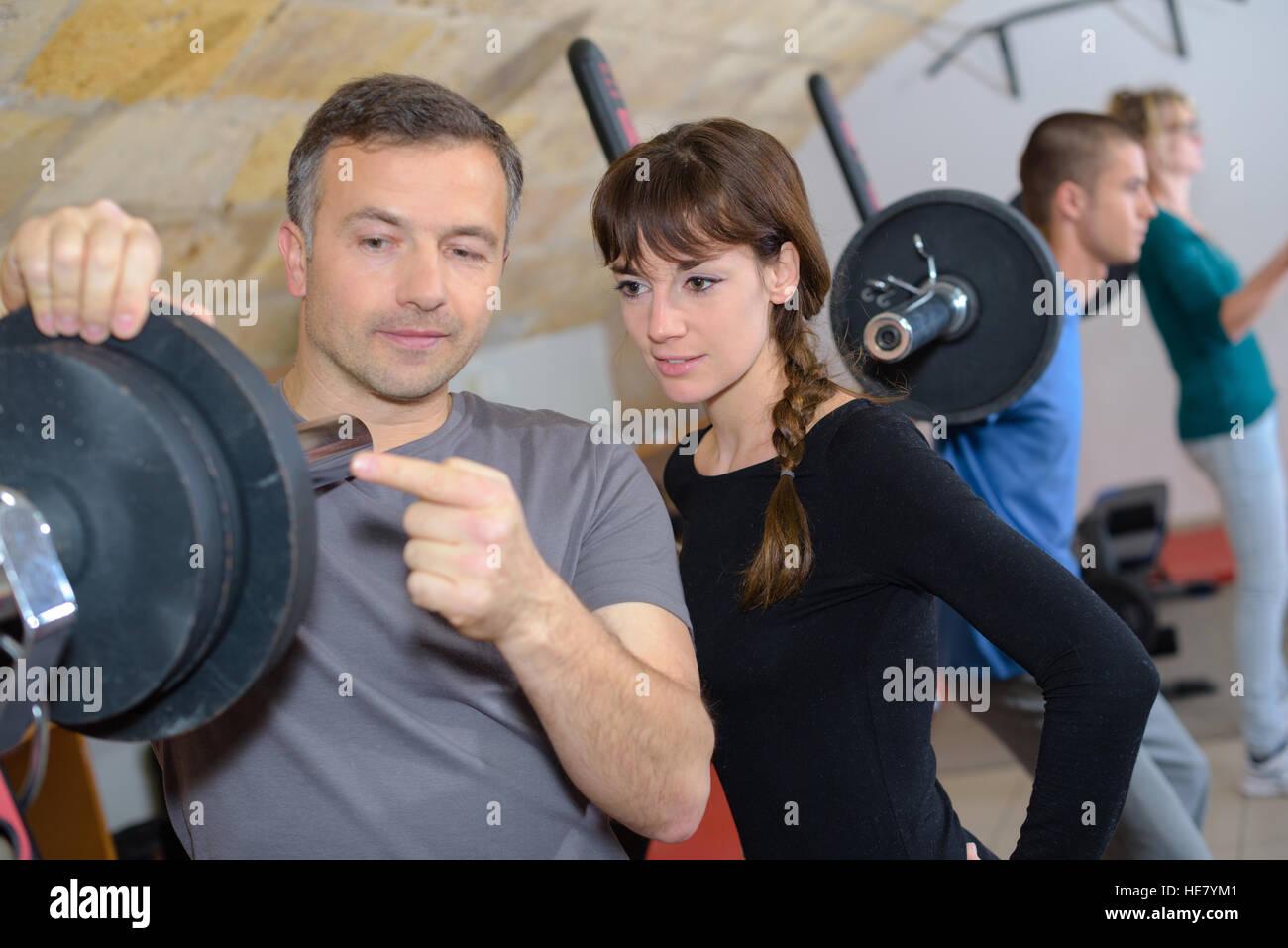 trainer explaining how to use training machine in a gym Stock Photo Alamy