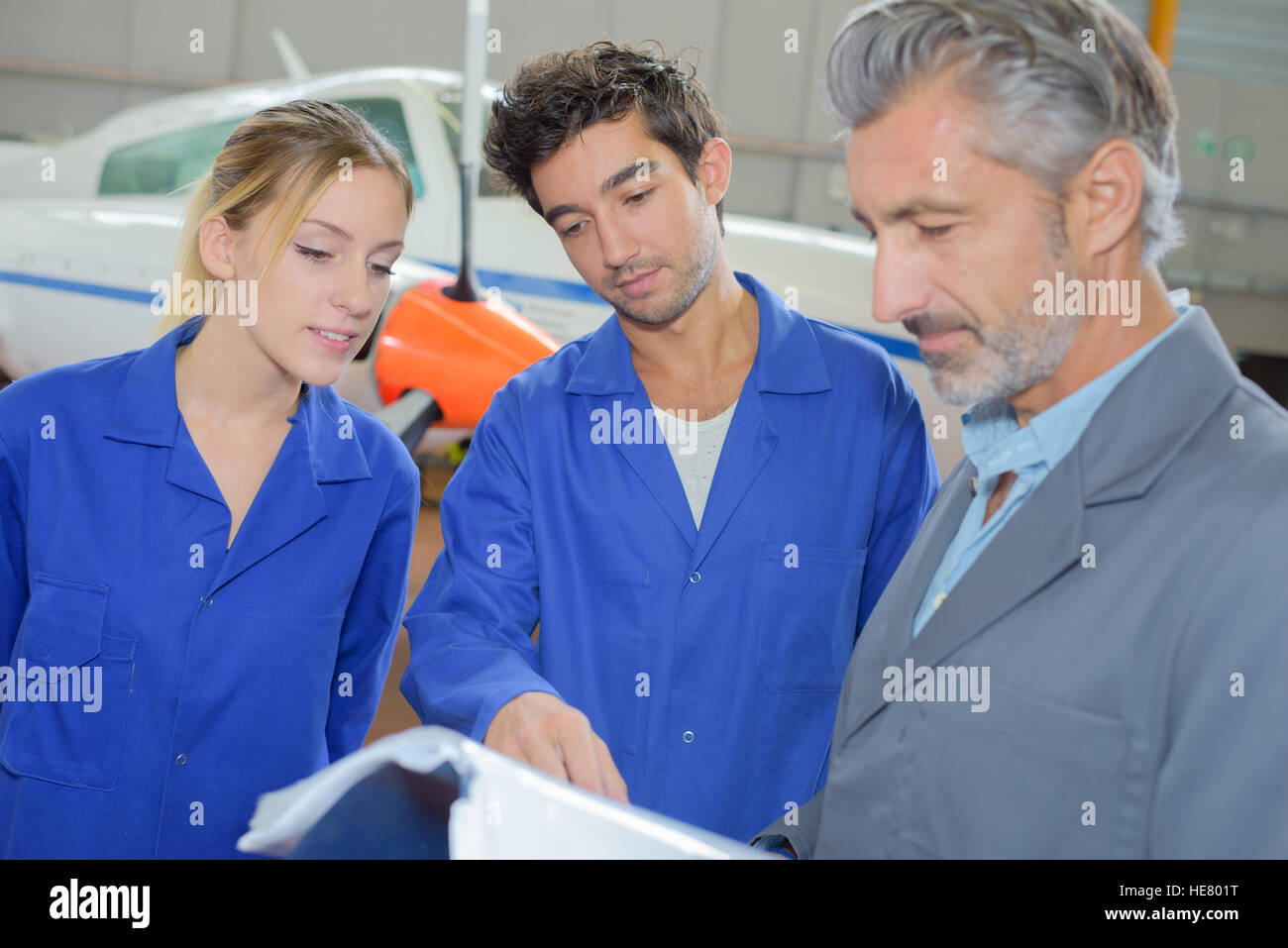 Students looking at reference book with instructor Stock Photo