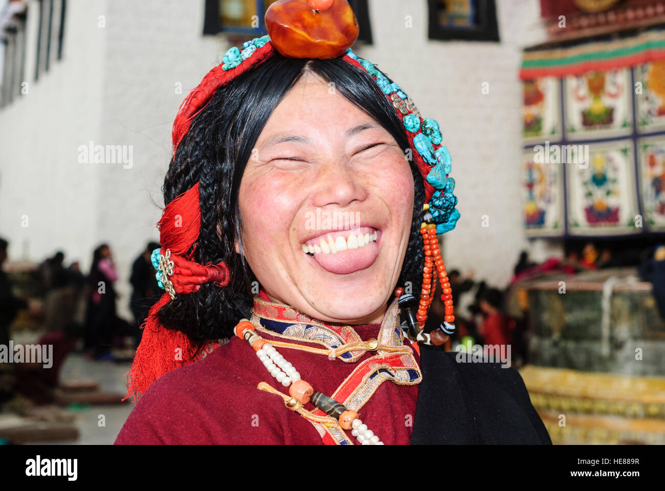 Lhasa: Jokhang Temple; Tibetan woman, headdress of turquoise, coral, amber and pearls worn at festivals like the Tibetan New Year (Losar), sticking ou Stock Photo