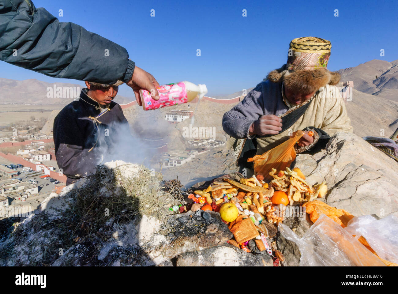 Gyantse: Tibetans sacrifice fruit and Chang (fermented barley beer) to the Tibetan New Year on a fire on a mountain in front of the Pelkor Chöde monas Stock Photo