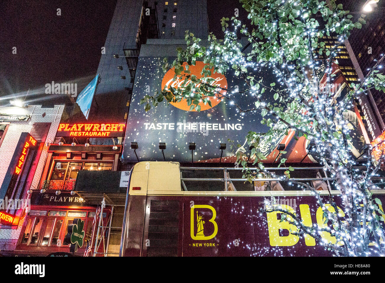lights of Theater district sparkle on 49th street with neon signs an illuminated billboard & street tree wrapped in star lights Stock Photo