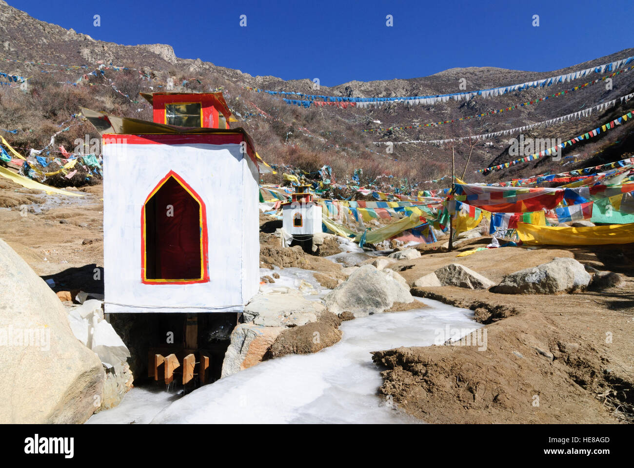 Samye: Prayer mills in the frozen water of a brook on the way to the Chim Puk hermitage, Tibet, China Stock Photo