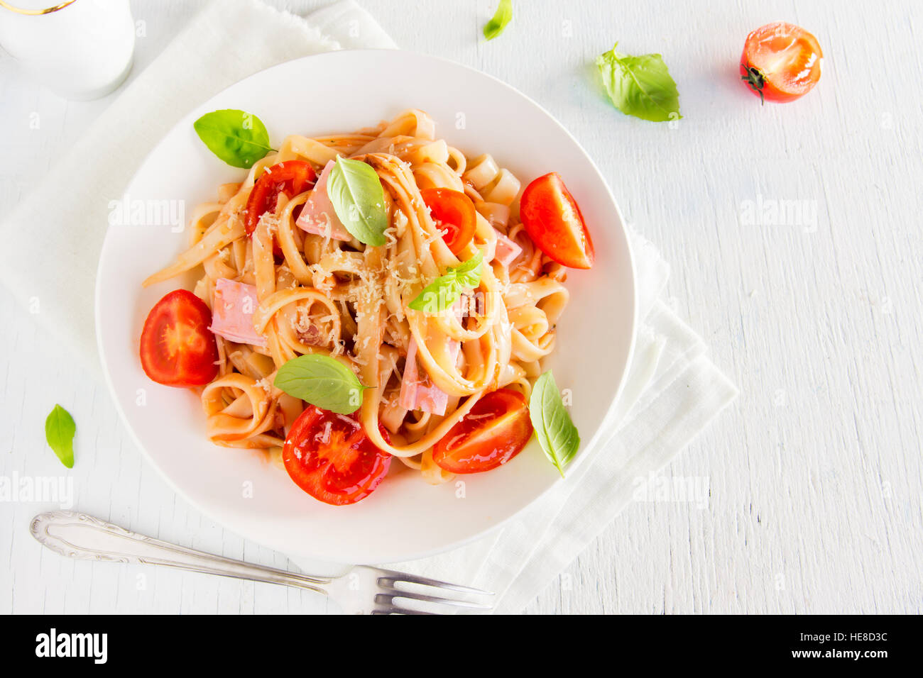 Tagliatelle pasta with ham, tomato sauce, cherry tomatoes and basil