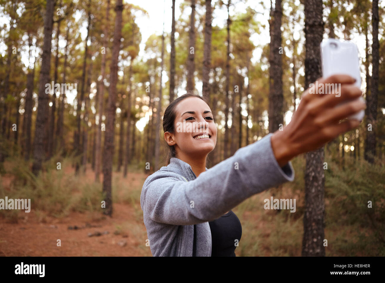 Lovely smiling young girl taking a selfie with her cell phone while ...