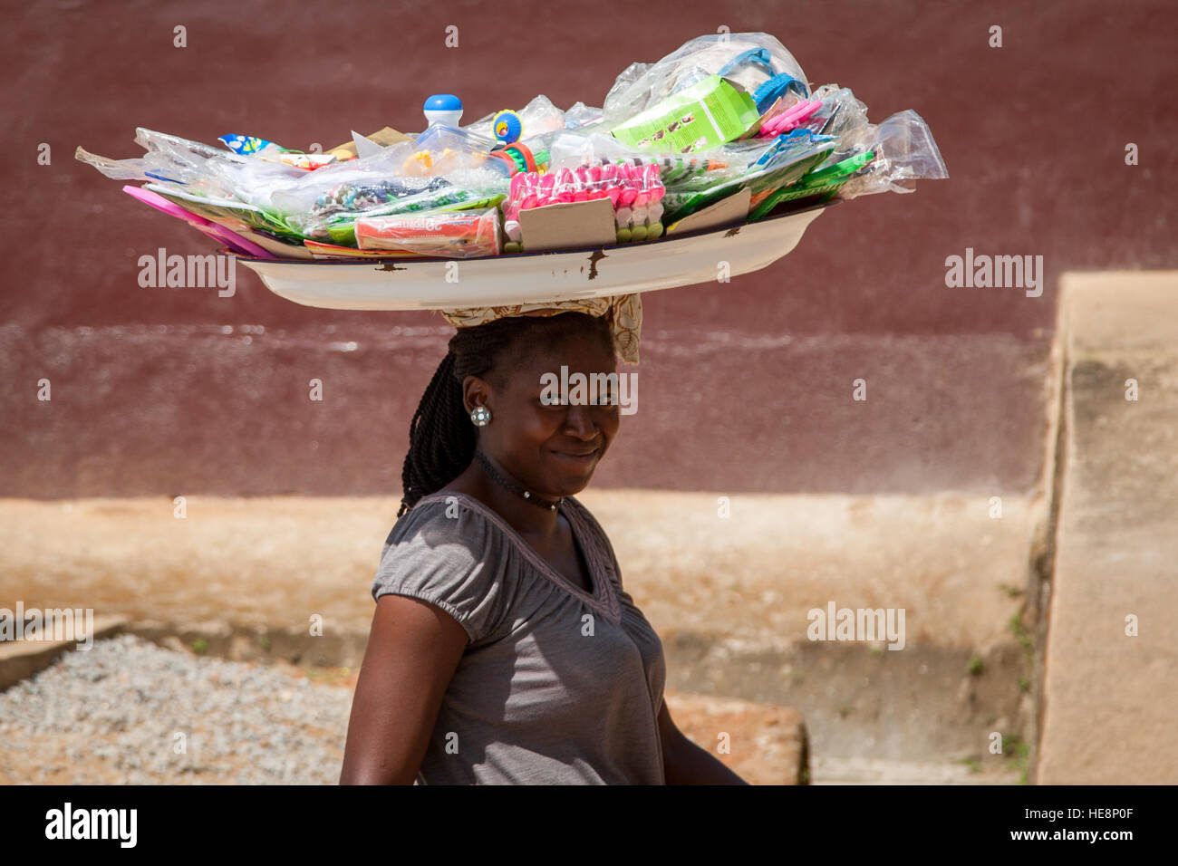 Woman smiling at camera and carrying a basket on her head Stock Photo