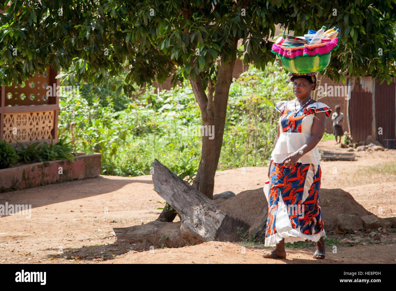 Woman looking at camera and carrying a basket on her head Stock Photo