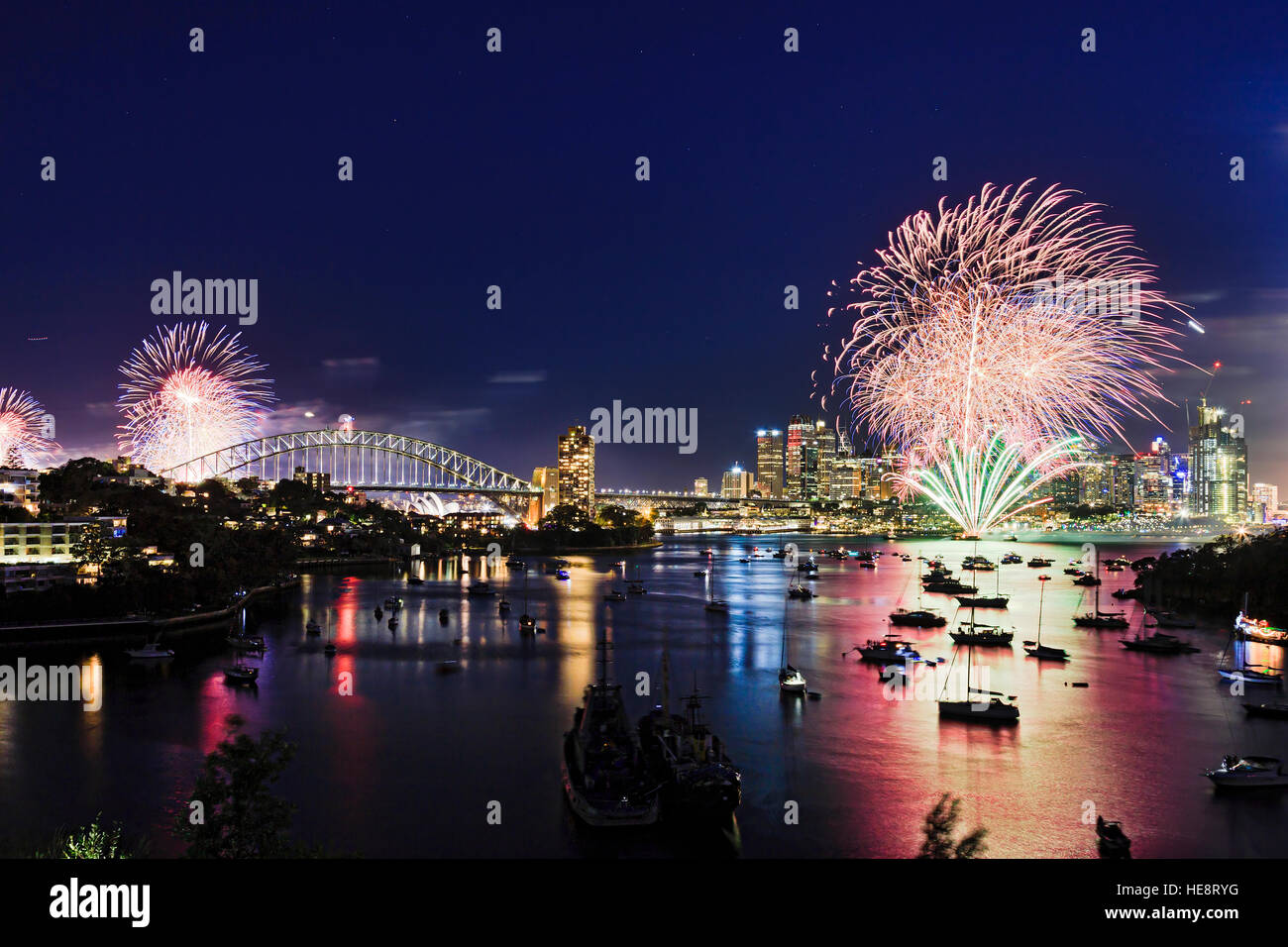 Sydney city landmarks panorama from Waverton elevated park at New Year Fireworks when bright light balls illuminate Harbour Bridge, skyscrapers and do Stock Photo