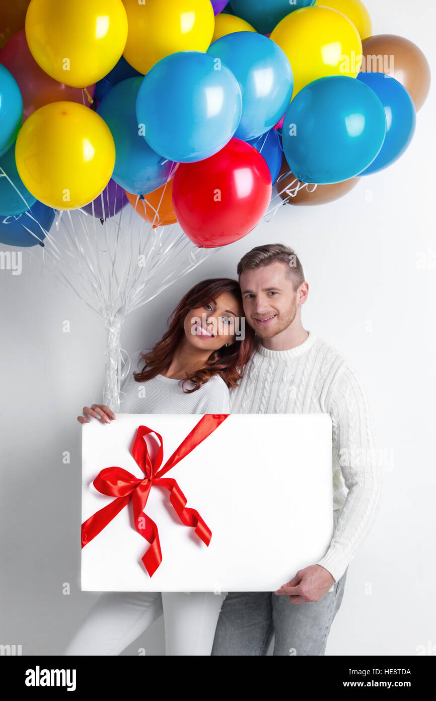 Young smiling couple with balloons and big gift box Stock Photo - Alamy