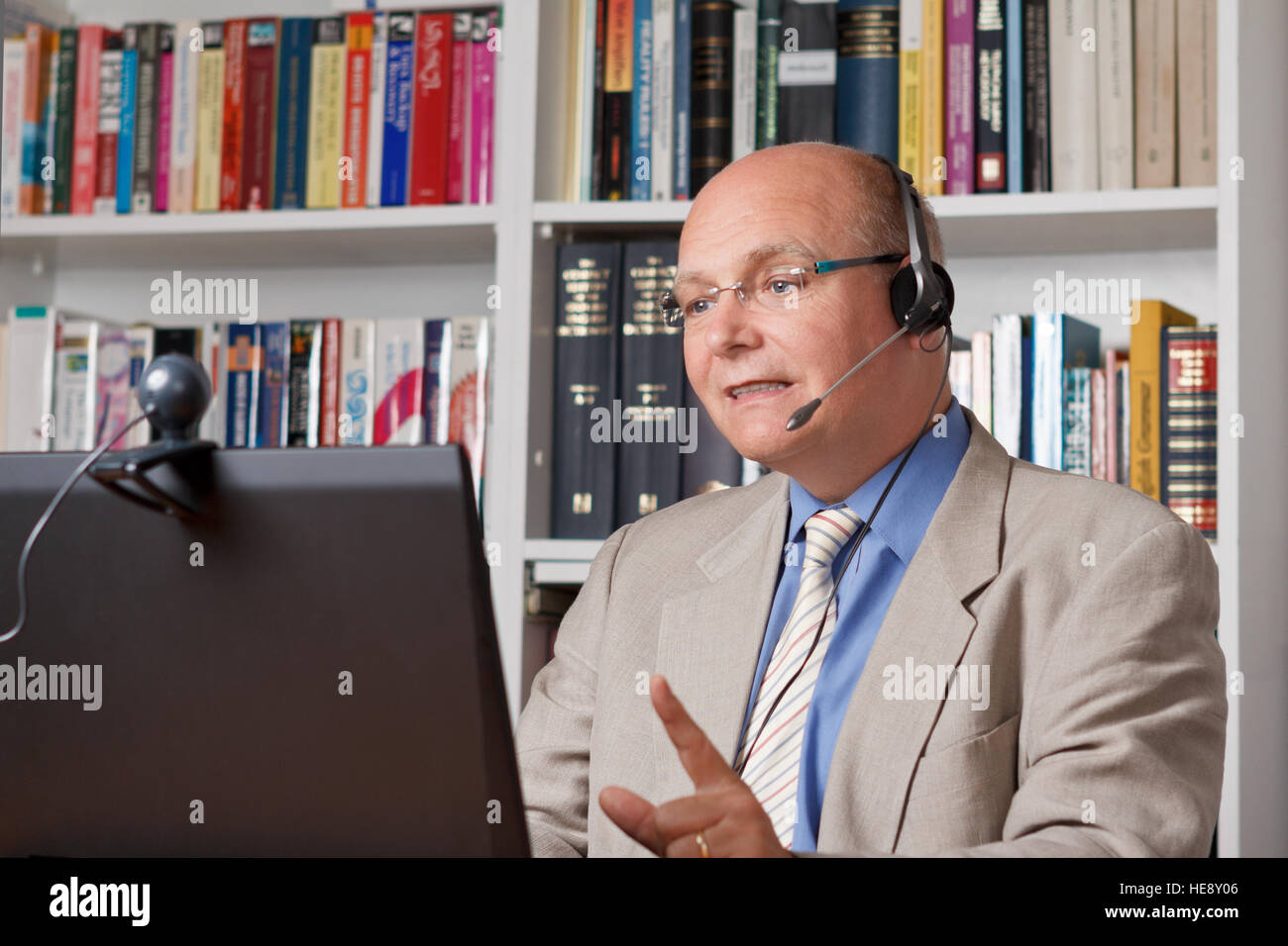 Lecturer at dinstance university with headset, computer and camera talking, holding an online lecture or mooc Stock Photo