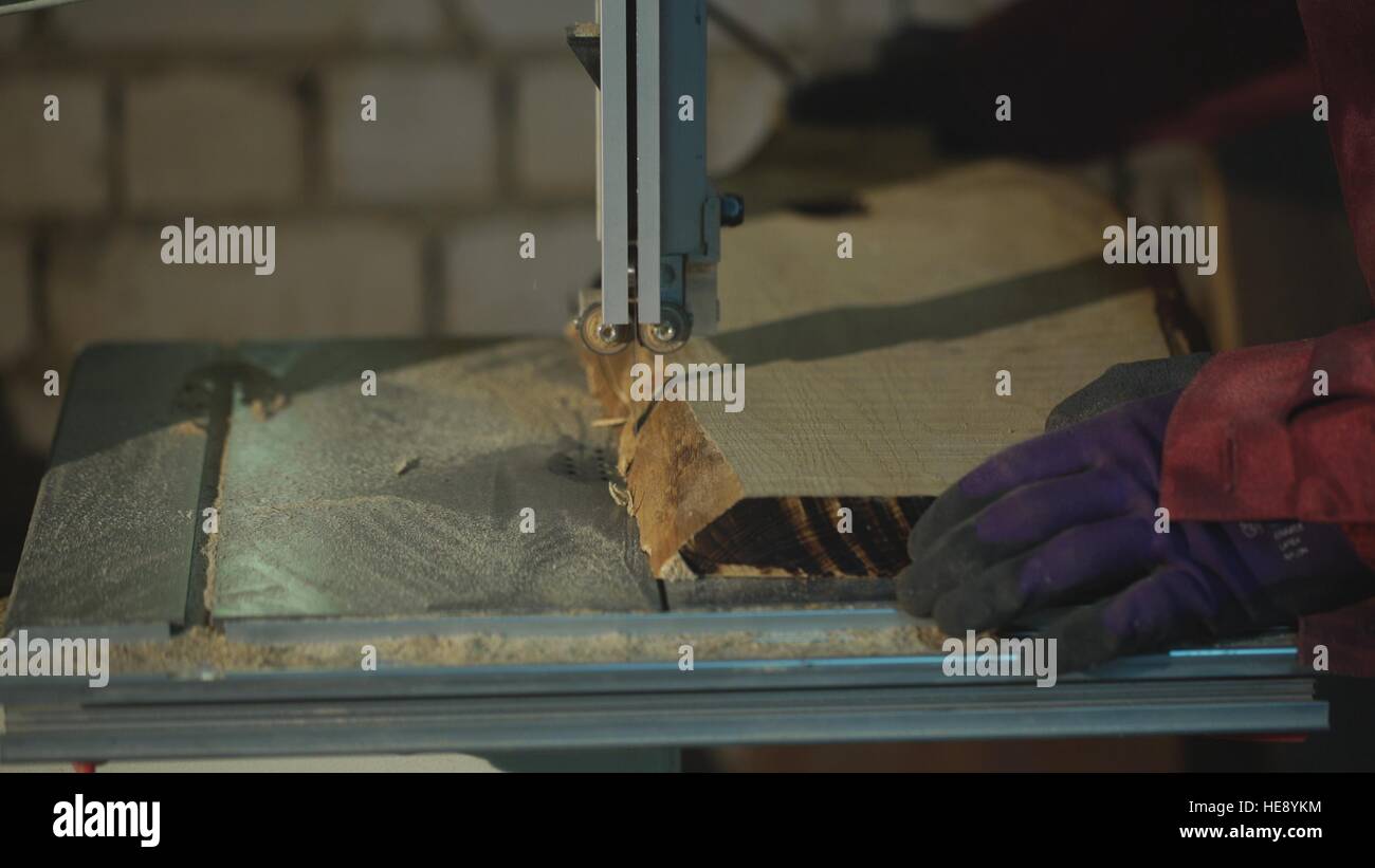 Carpenter cuts the board on rotating circular saw blade Worker hands
